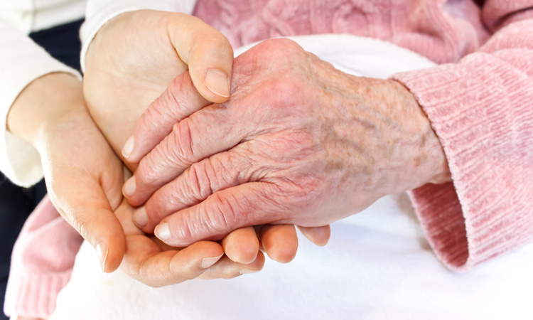 Caregiver holding elderly woman's hand