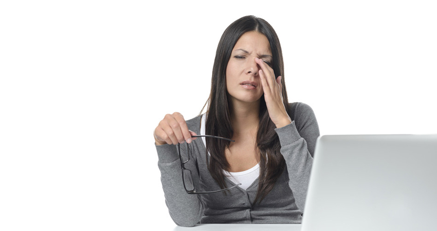 Woman rubbing her eyes in front of laptop computer