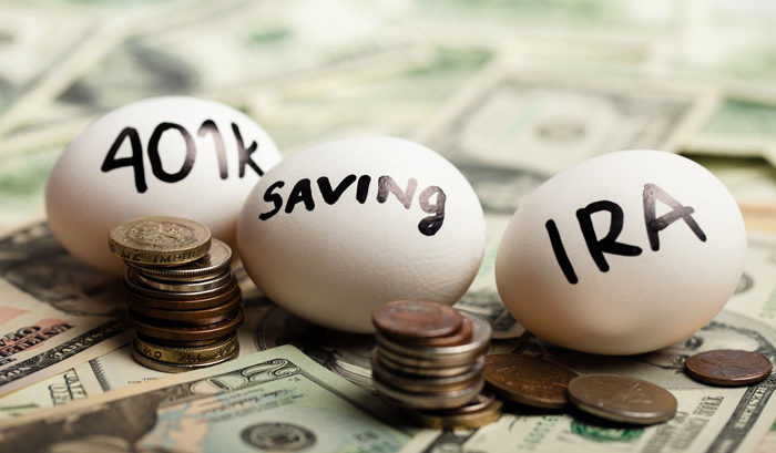 Three eggs with 401(k) saving and IRA written on them laying on top of dollar bills and coins
