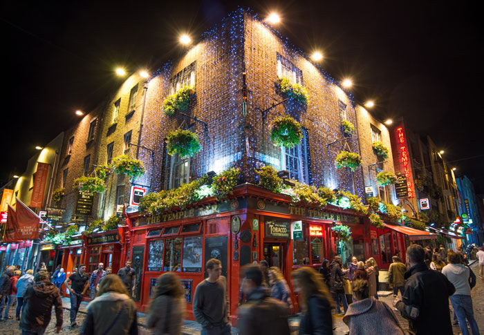 The Temple Bar lit up at night in Dublin Ireland with crowds of people around
