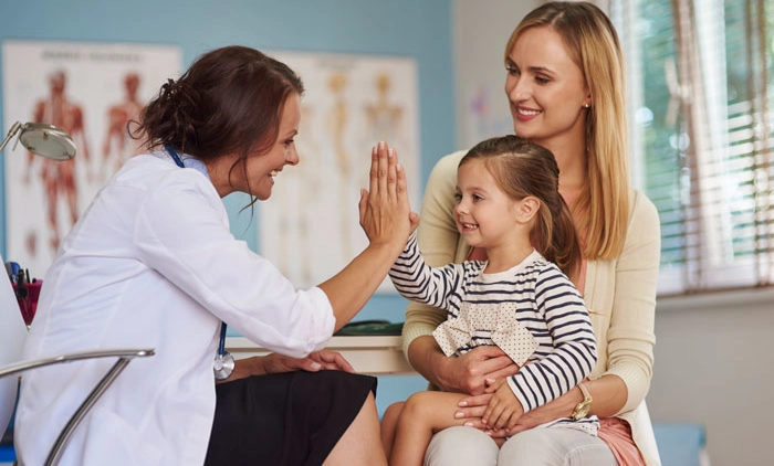 Healthcare provider high-fiving young child and mother