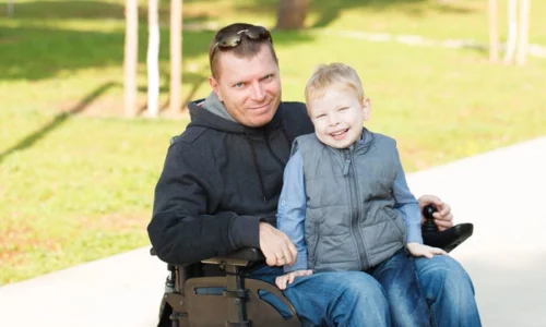Man In Wheelchair With Son On Lap