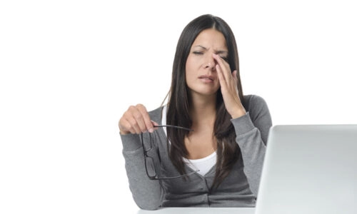 Woman Rubbing Her Eyes In Front Of Laptop Computer