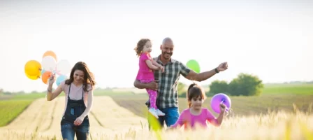 Happy Family Playing In A Field With Balloons