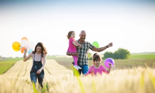 Happy Family Playing In A Field With Balloons