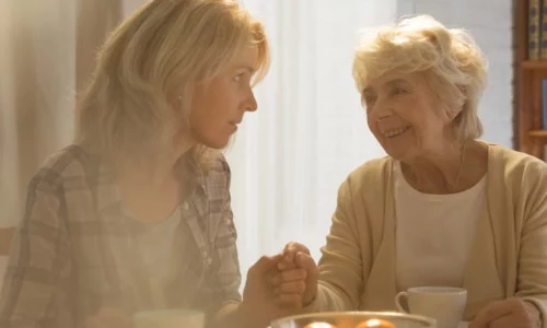 Middle-aged Woman Speaking With Elderly Mother At Dining Room Table