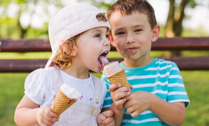 children eating ice cream cones on a park bench