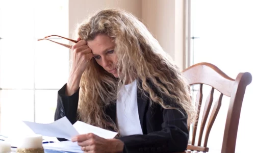 Stressed Woman Reviewing Paperwork At Home